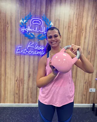 Kleos Entrenamiento chica posa sonriente con pesa